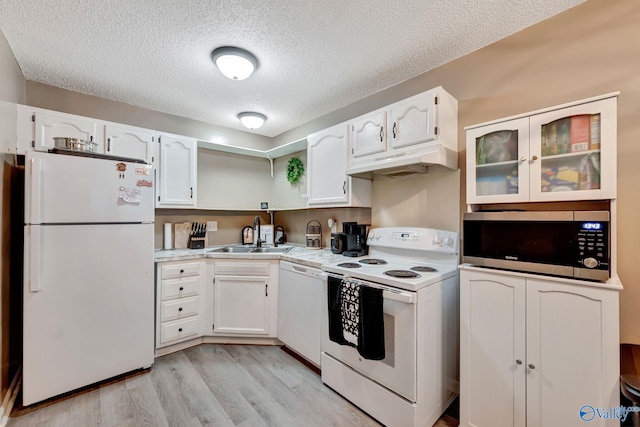 kitchen with white appliances, a sink, white cabinets, and under cabinet range hood