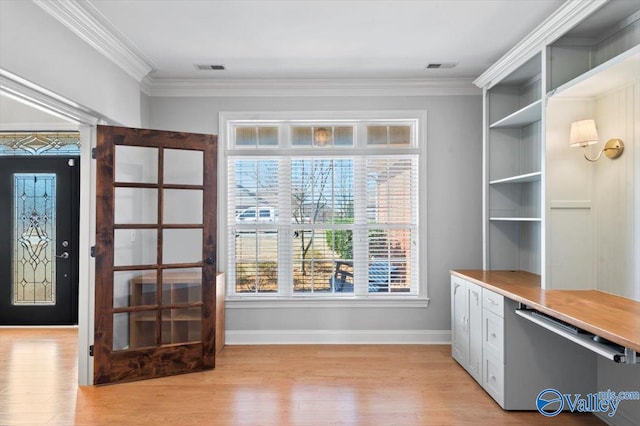 interior space with ornamental molding, light wood-style flooring, and baseboards