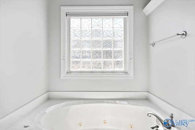 bathroom with a tub with jets and a healthy amount of sunlight