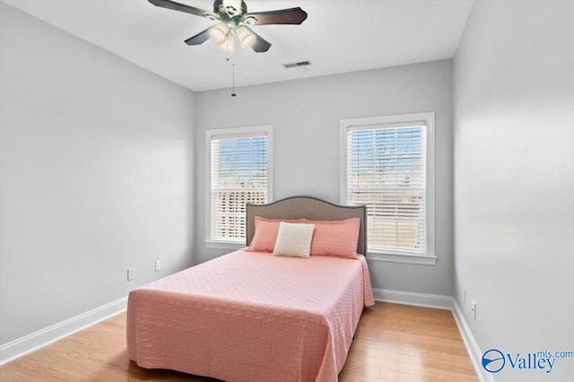 bedroom with light wood-style flooring, visible vents, ceiling fan, and baseboards