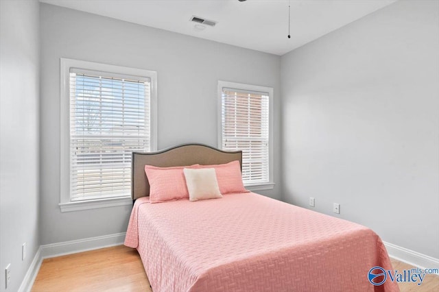 bedroom with light wood-style floors, visible vents, and baseboards