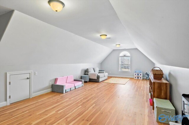 additional living space featuring vaulted ceiling, wood finished floors, and baseboards