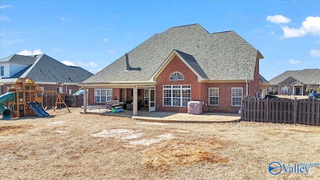 back of property with a playground, fence, a patio, and brick siding