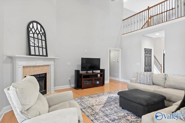 living room with stairs, a fireplace, wood finished floors, and baseboards