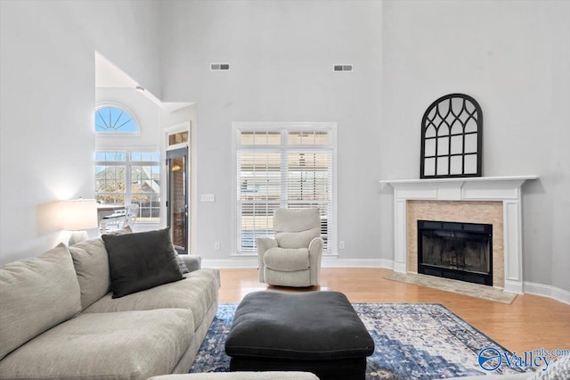 living area featuring baseboards, visible vents, wood finished floors, and a tile fireplace