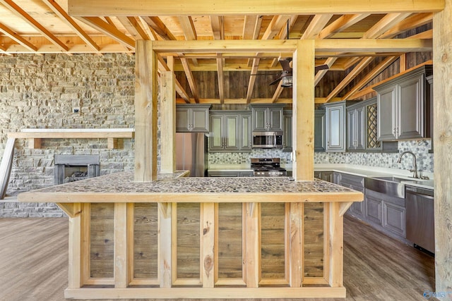 kitchen featuring sink, lofted ceiling with beams, backsplash, wood-type flooring, and appliances with stainless steel finishes