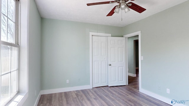 unfurnished bedroom with a closet, a textured ceiling, baseboards, and wood finished floors