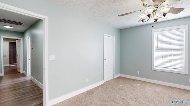 unfurnished room featuring visible vents, ceiling fan, a textured ceiling, and baseboards