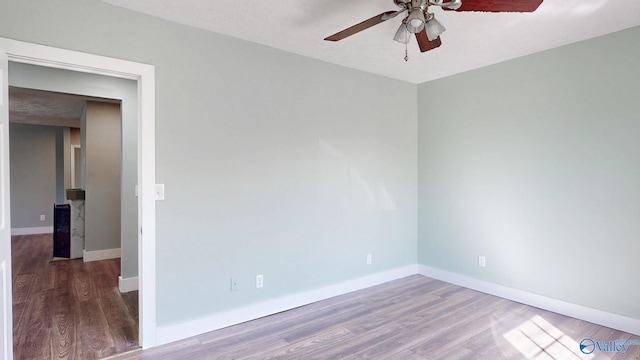 empty room with ceiling fan, baseboards, and wood finished floors