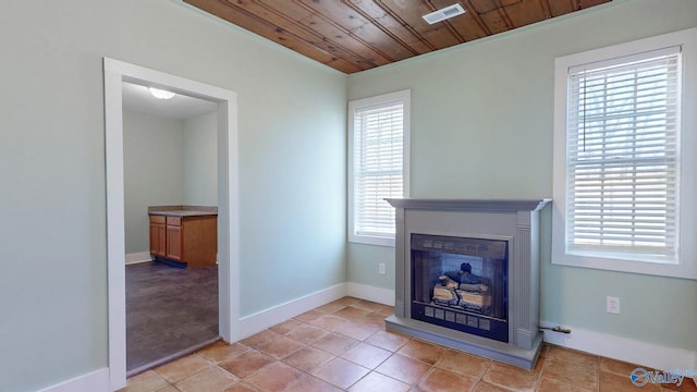 unfurnished living room featuring wooden ceiling, plenty of natural light, a fireplace, and visible vents