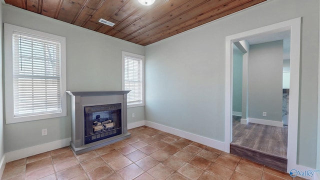 unfurnished living room with visible vents, baseboards, a fireplace, tile patterned flooring, and wood ceiling