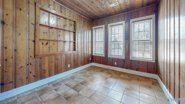 tiled spare room featuring visible vents, wooden walls, a healthy amount of sunlight, and wooden ceiling