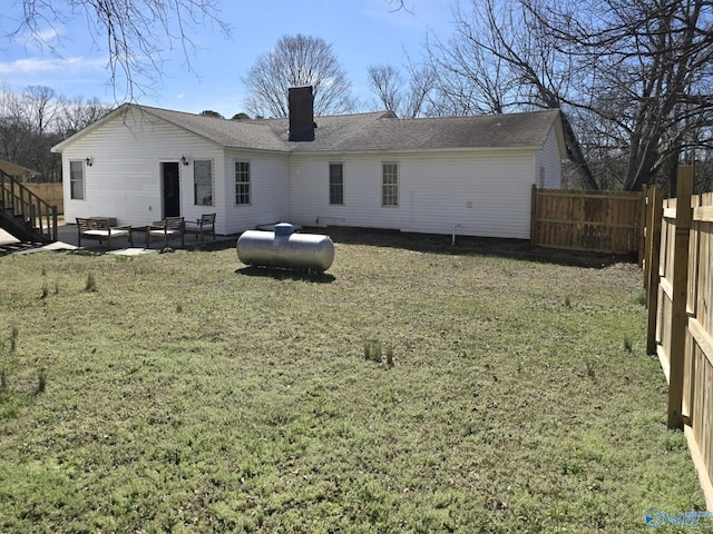 rear view of house with fence, a lawn, and a chimney