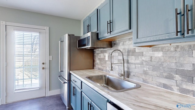 kitchen featuring stainless steel microwave, backsplash, baseboards, light countertops, and a sink