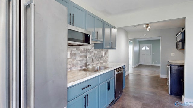 kitchen with blue cabinetry, a sink, decorative backsplash, light countertops, and appliances with stainless steel finishes