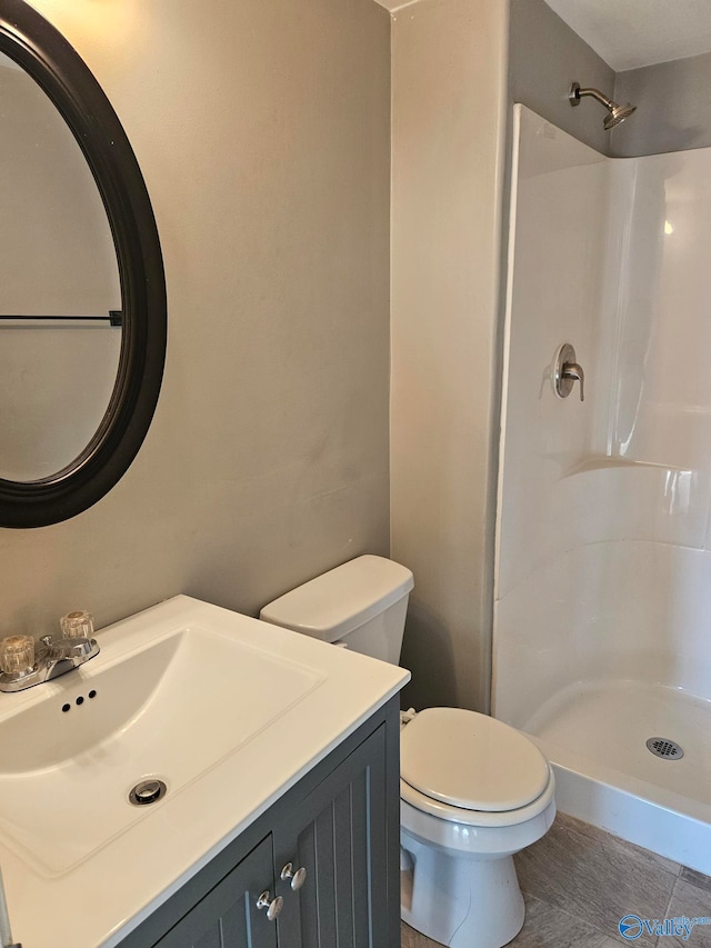 bathroom with walk in shower, vanity, and toilet