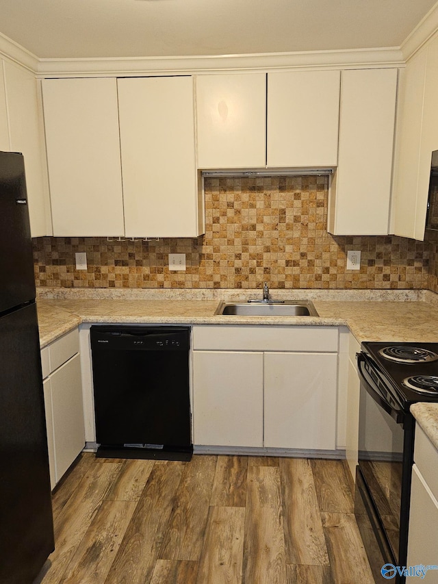 kitchen with sink, hardwood / wood-style flooring, white cabinetry, black appliances, and decorative backsplash