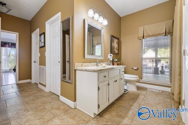 bathroom with baseboards, vanity, and toilet