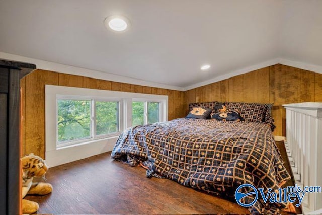 bedroom with wood walls, vaulted ceiling, and wood finished floors