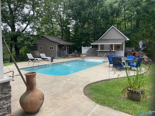 outdoor pool featuring an outbuilding, a patio, fence, and a storage structure