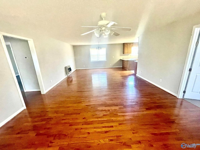 unfurnished living room featuring a textured ceiling, dark hardwood / wood-style flooring, and ceiling fan with notable chandelier