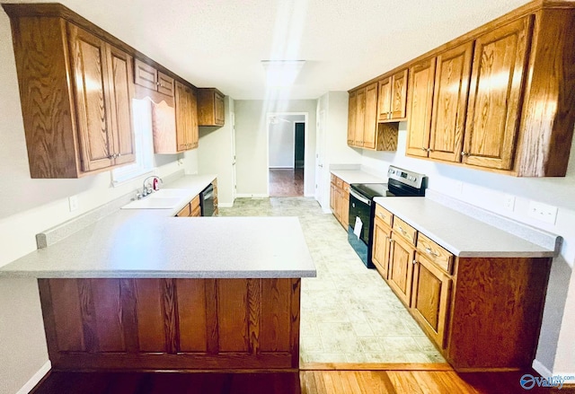 kitchen featuring appliances with stainless steel finishes, kitchen peninsula, sink, and light hardwood / wood-style floors