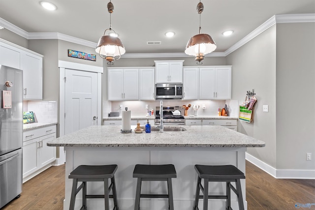 kitchen with visible vents, appliances with stainless steel finishes, a breakfast bar area, and ornamental molding