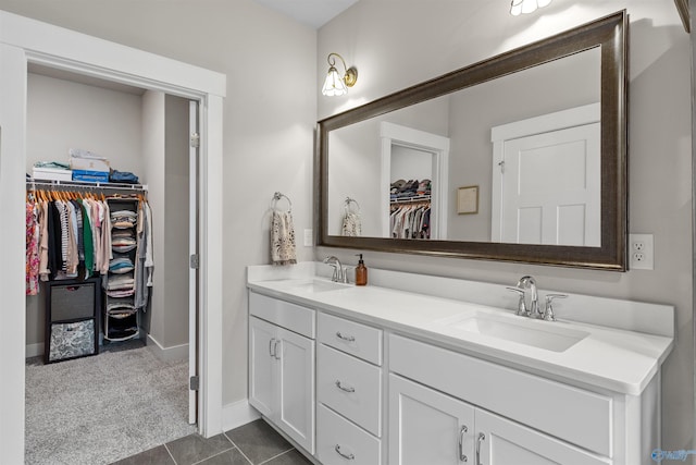 full bathroom featuring double vanity, a spacious closet, baseboards, and a sink