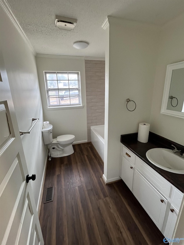 full bathroom featuring wood-type flooring, ornamental molding, vanity, toilet, and a textured ceiling