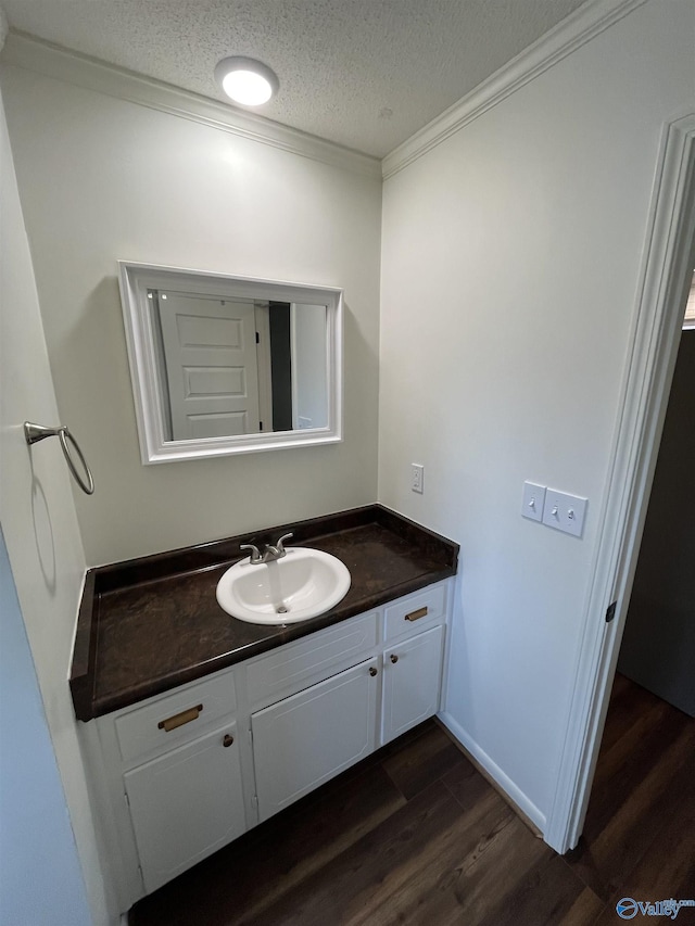 bathroom featuring ornamental molding, wood-type flooring, vanity, and a textured ceiling