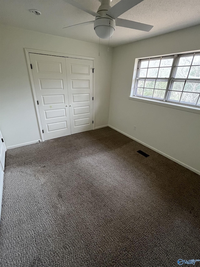 unfurnished bedroom with ceiling fan, carpet floors, a closet, and a textured ceiling