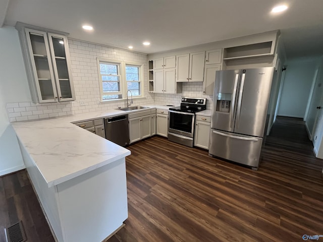 kitchen featuring appliances with stainless steel finishes, dark hardwood / wood-style floors, kitchen peninsula, and sink