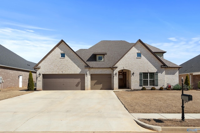 french country home with a garage, brick siding, driveway, and a shingled roof