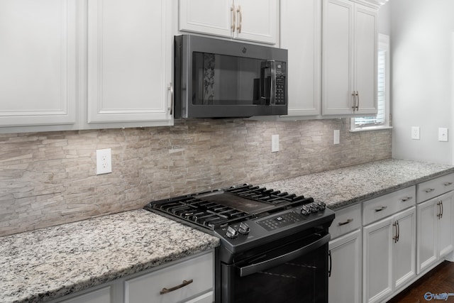 kitchen with black appliances, tasteful backsplash, light stone counters, and white cabinets