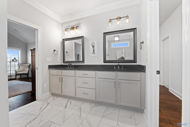 full bath with double vanity, marble finish floor, ornamental molding, and a sink