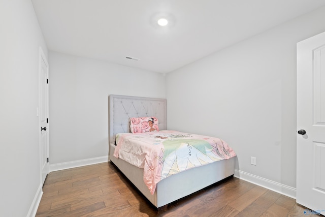 bedroom with baseboards, visible vents, and hardwood / wood-style floors