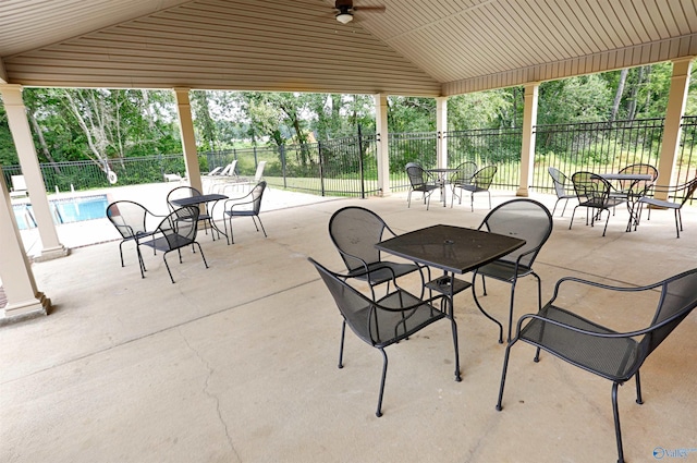 view of patio / terrace featuring outdoor dining area, fence, and a community pool