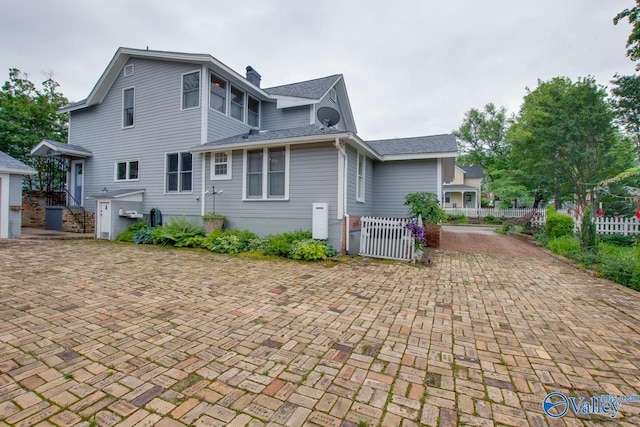 717 NE Eustis Ave, Huntsville, AL 35801 - back of house featuring fence, a gate, a chimney, and a shingled roof