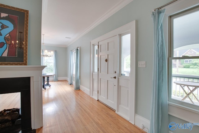 717 NE Eustis Ave, Huntsville, AL 35801 - foyer featuring ornamental molding, light wood finished floors, a chandelier, baseboards, and a fireplace