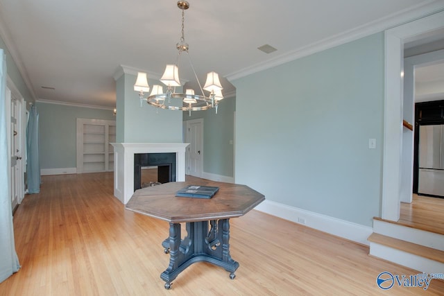 717 NE Eustis Ave, Huntsville, AL 35801 - dining space with a chandelier, light wood-type flooring, baseboards, crown molding, and a fireplace