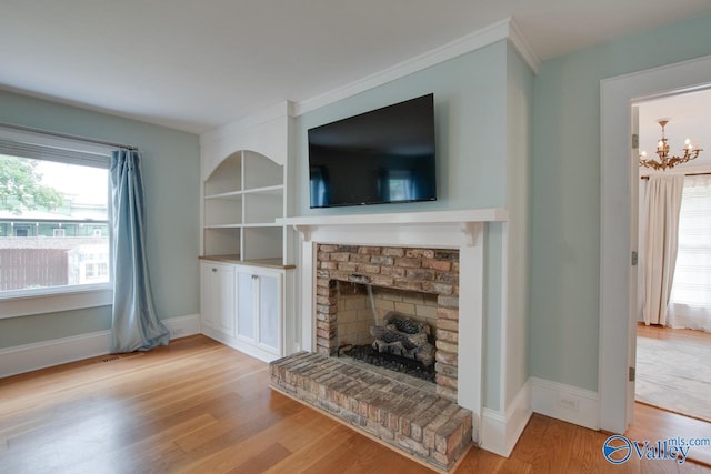 717 NE Eustis Ave, Huntsville, AL 35801 - unfurnished living room featuring wood finished floors, a fireplace, a chandelier, baseboards, and ornamental molding
