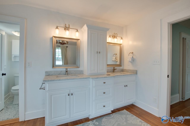 717 NE Eustis Ave, Huntsville, AL 35801 - full bath featuring wood finished floors, baseboards, double vanity, and toilet