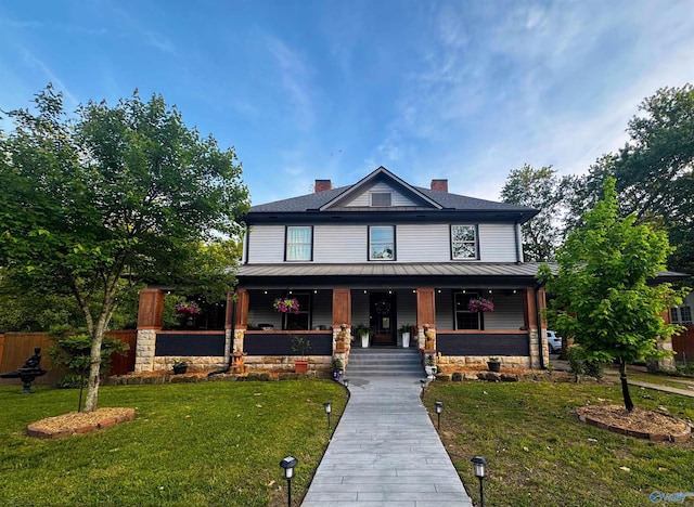 view of front facade featuring fence, covered porch, a chimney, and a front lawn