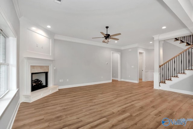 unfurnished living room with crown molding, a fireplace, stairway, ceiling fan, and light wood-type flooring