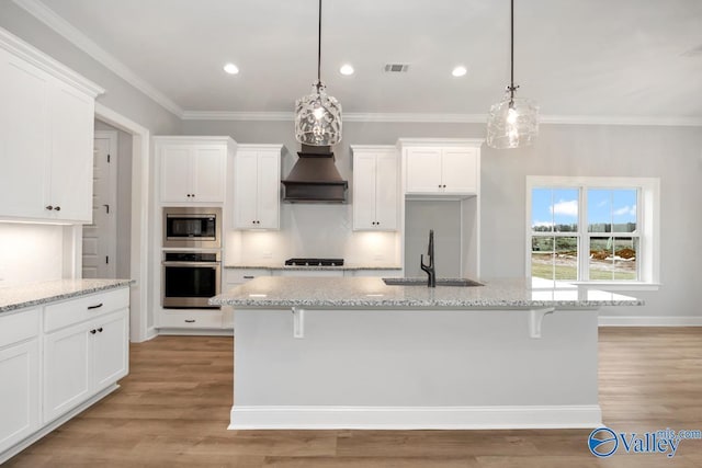 kitchen featuring visible vents, appliances with stainless steel finishes, a kitchen island with sink, white cabinetry, and a sink