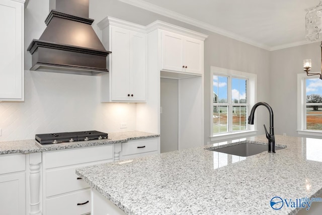 kitchen featuring custom range hood, light stone counters, white cabinets, and a sink