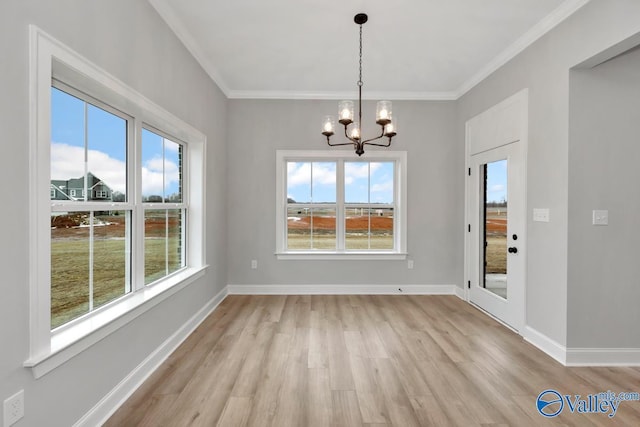 unfurnished dining area featuring light wood-type flooring, a healthy amount of sunlight, a notable chandelier, and baseboards