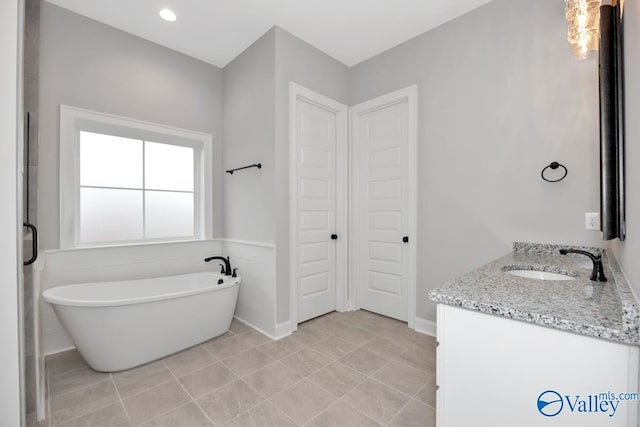 bathroom featuring a soaking tub, vanity, and tile patterned floors