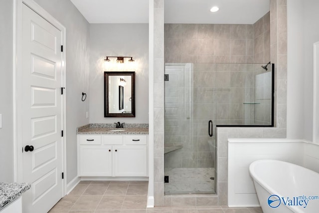 bathroom with tile patterned flooring, a soaking tub, a shower stall, and vanity