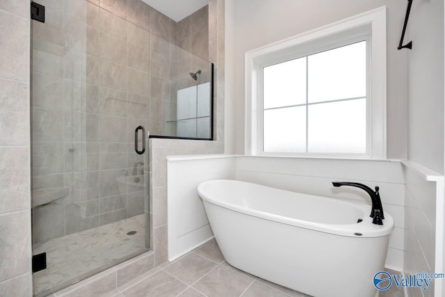 bathroom with a shower stall, tile walls, a freestanding bath, and tile patterned floors